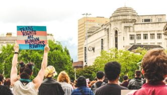 Activist holding up a trans flag sign reading "trans rights are human rights"