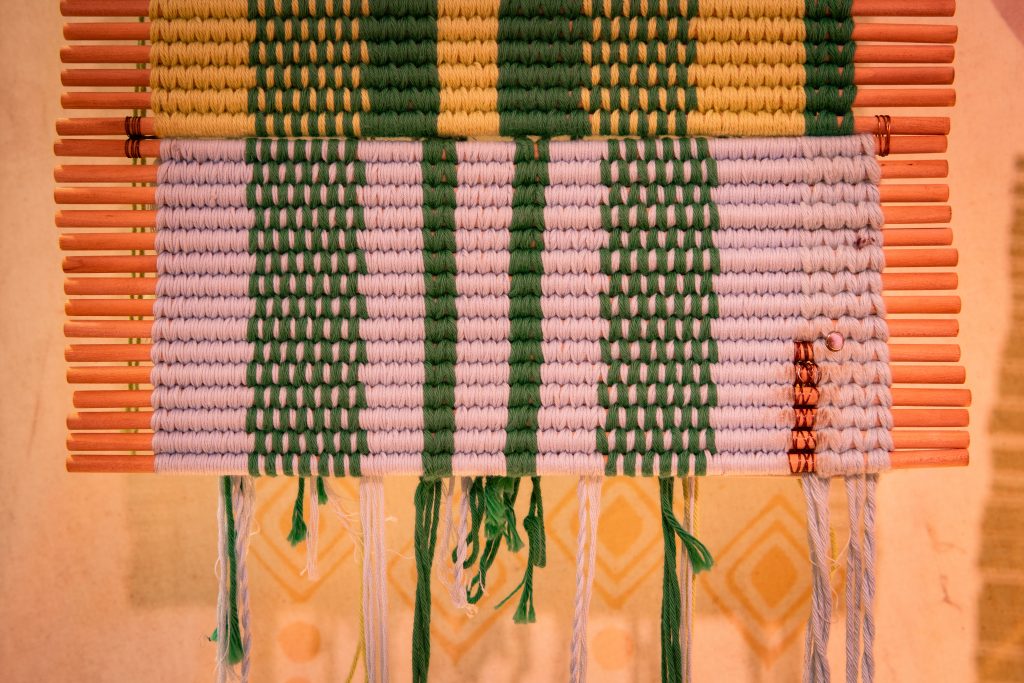 A close-up of the one of the tapestries woven in white, green and yellow colours.