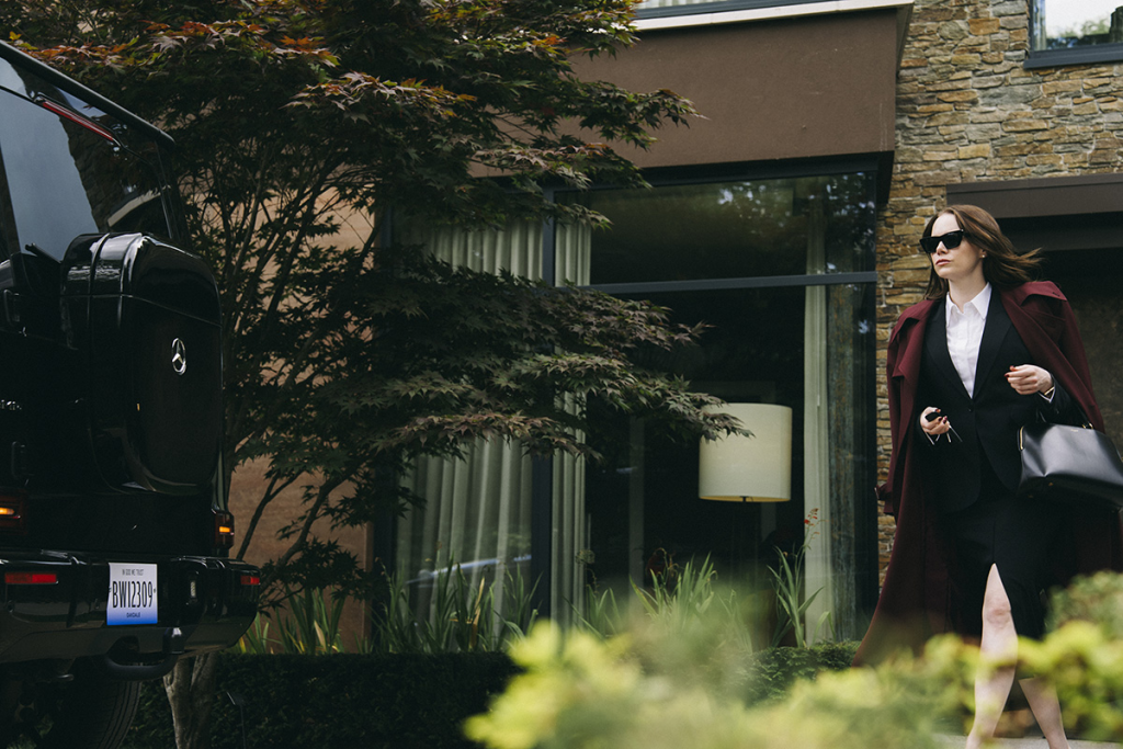 Image of Emma Stone walking out of a house to a car. 