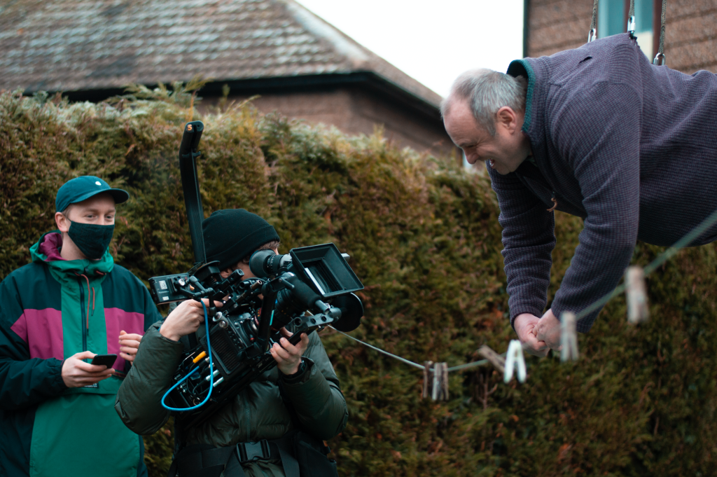 Image of an Oulton resident suspended in the air, hanging onto a washing line as Alfie gives directions.