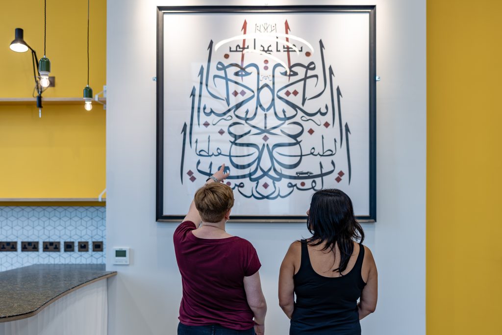 Image of two people looking at artwork on the wall.