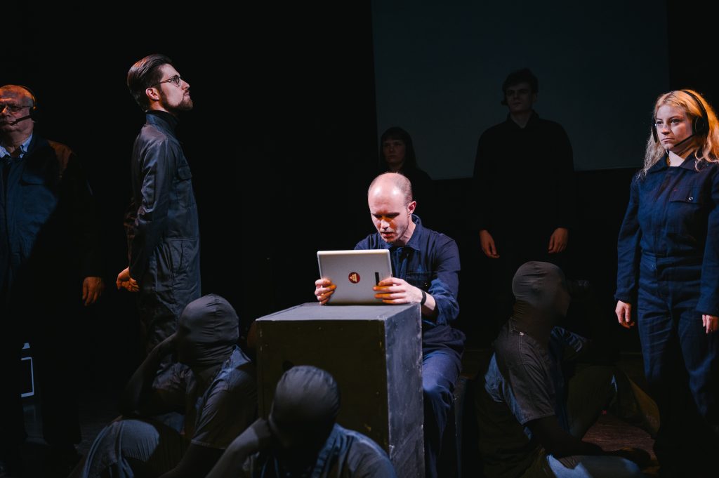 Connor Houlton as Winston Smith, with ensemble and figments, in Leeds Arts Centre’s 1984. 