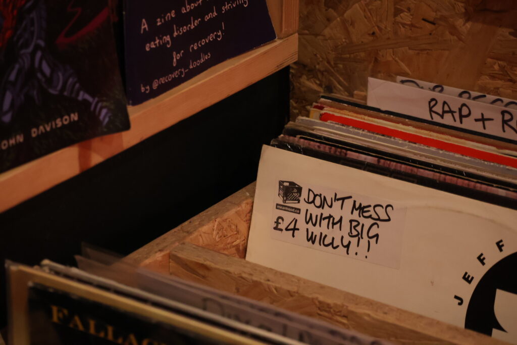 Vinyl records displayed in crates, with handwritten labels and a £4 "Don't Mess With Big Willy!" record in the foreground.