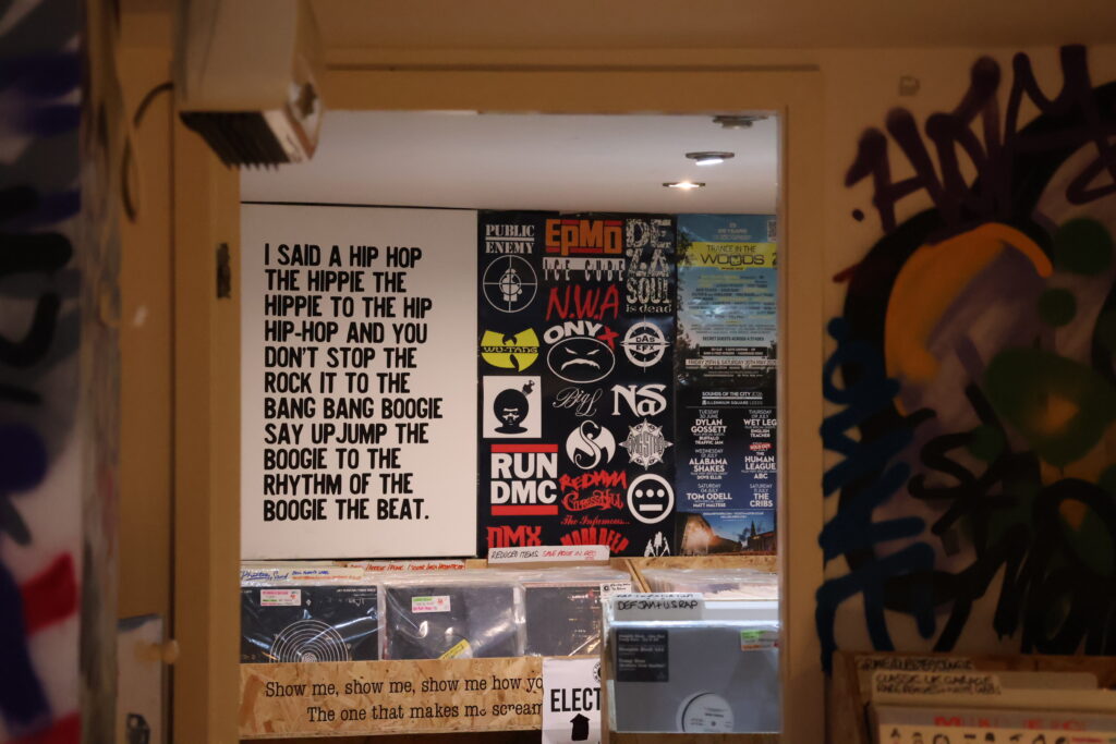 Basement vinyl room at Leeds record shop Meanhood, featuring crates of records, hip-hop posters and graffiti-covered walls.