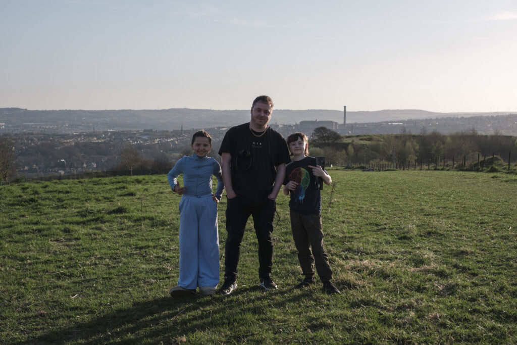 Elif Riley and Logan Ludbrook stand either side of Jordon in a field.