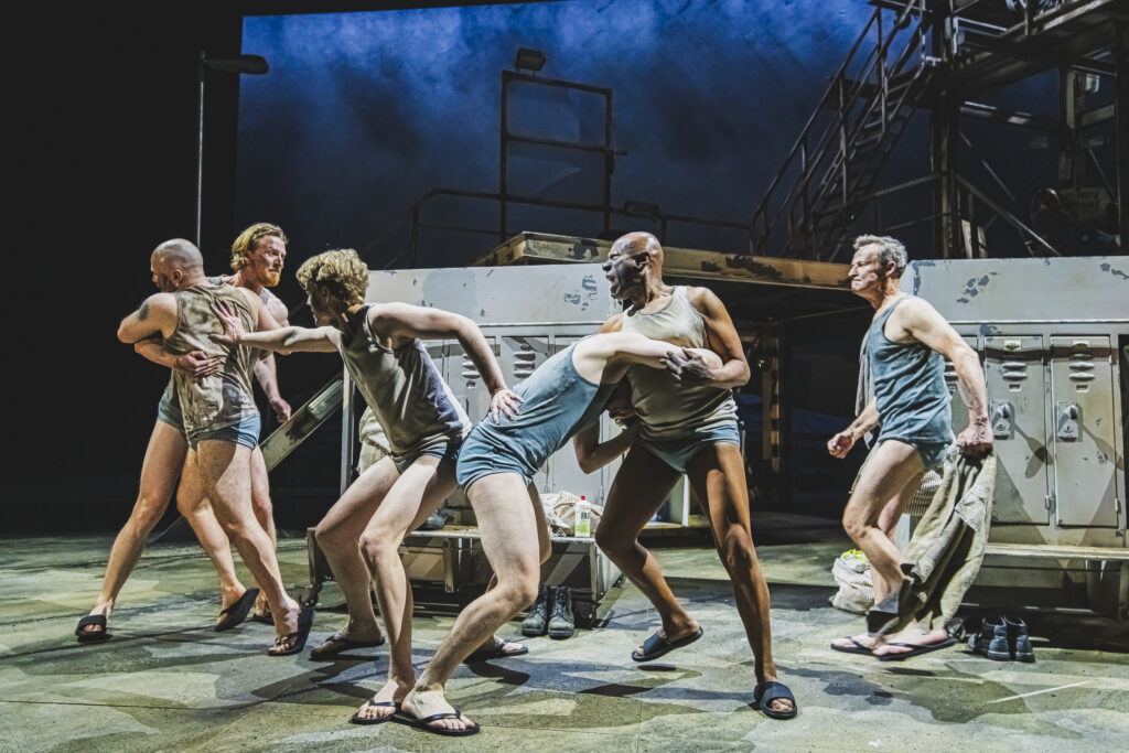 Several men in vests and underpants fight each other.