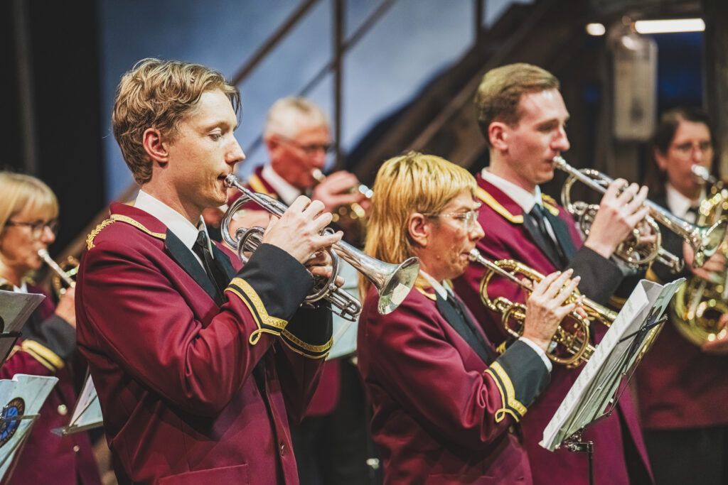 A close up shot featuring two members of the band in red suits playing the trumpet.