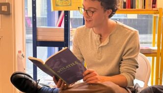 Tom Branfoot sits in a bookshop reading 'Volatile'.