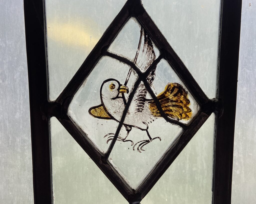 Stained glass window featuring a diamond shape with a bird inside.