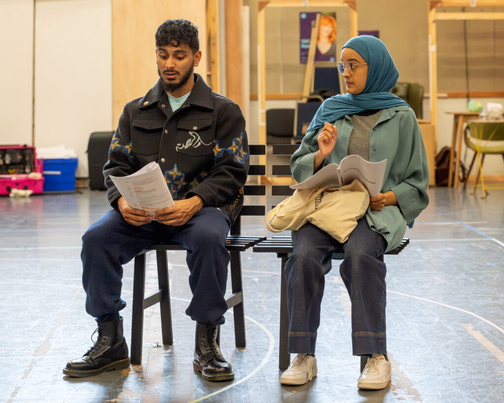 Kashif Ghole (Bilal) and Humera Syed (Hafsah) sit on a bench. Humera gives Kashif a pointed look.