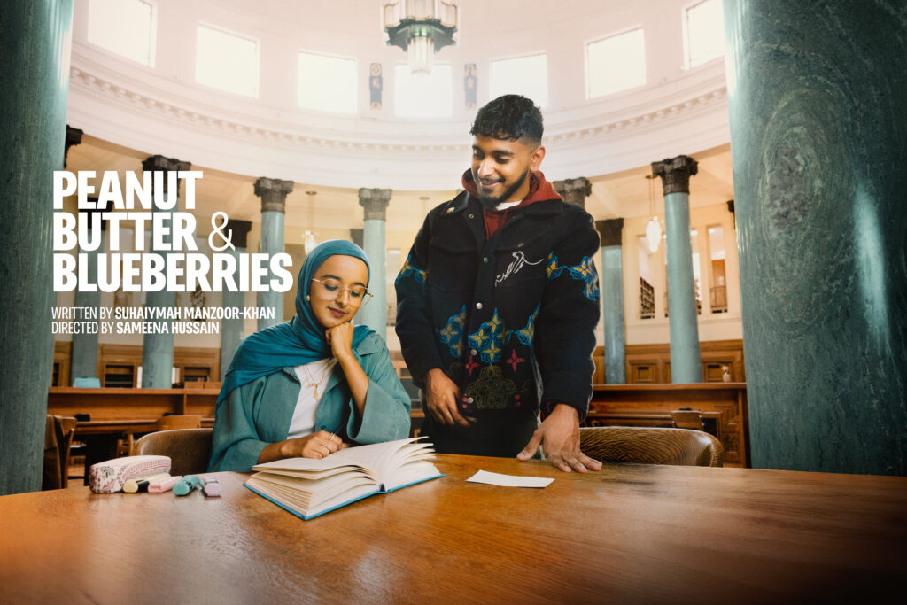 Hafsah looks doen at a book laid open on a table while Bilal stands next to her.