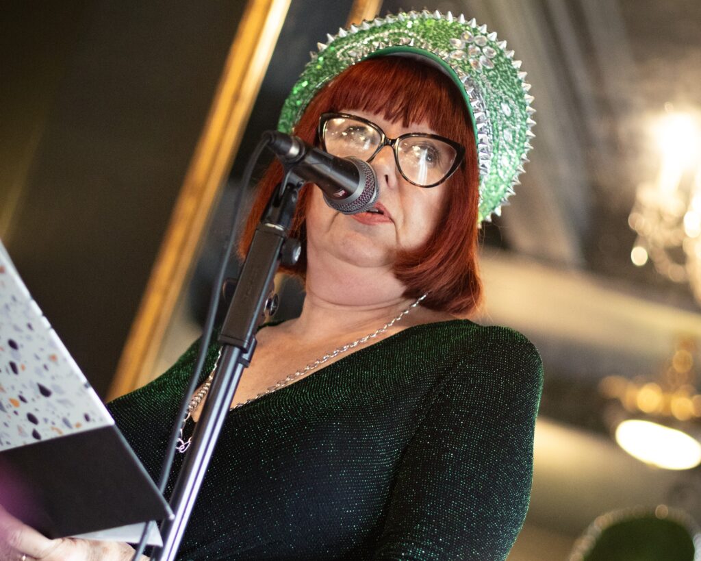 Julie Baird, aka Radical Annie, performs her poetry wearing a green sequinned outfit and spiked headpiece.