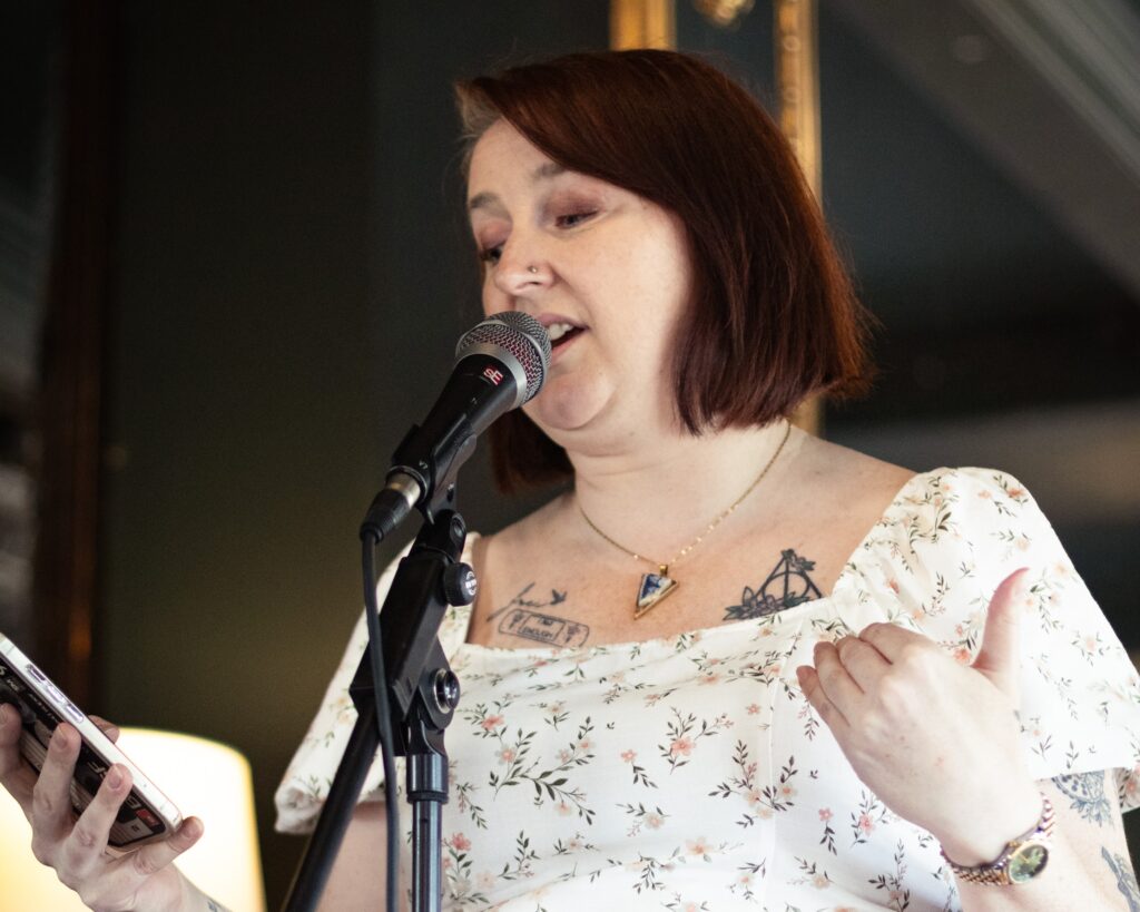 Katie-Lou Clarkson speaking into a microphone while holding her phone.